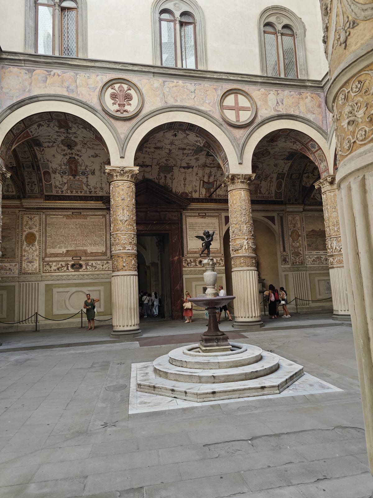 The painted arcades of Palazzo Vecchio's courtyard, frescoed walls and gilded columns around a small fountain topped with a putto