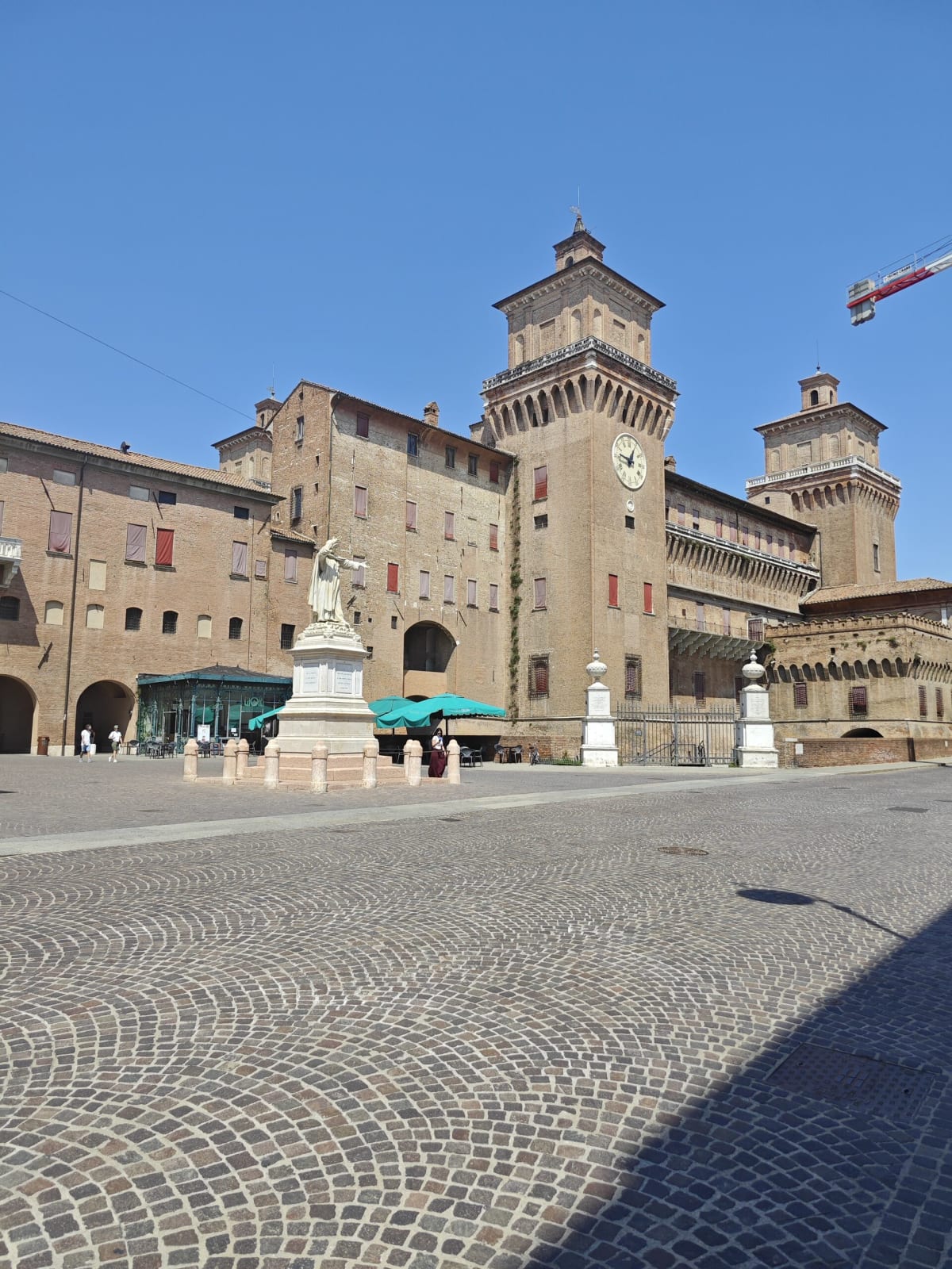 The Castello Estense from the square, a marble statue in front of its gatehouse and the tall clock tower behind