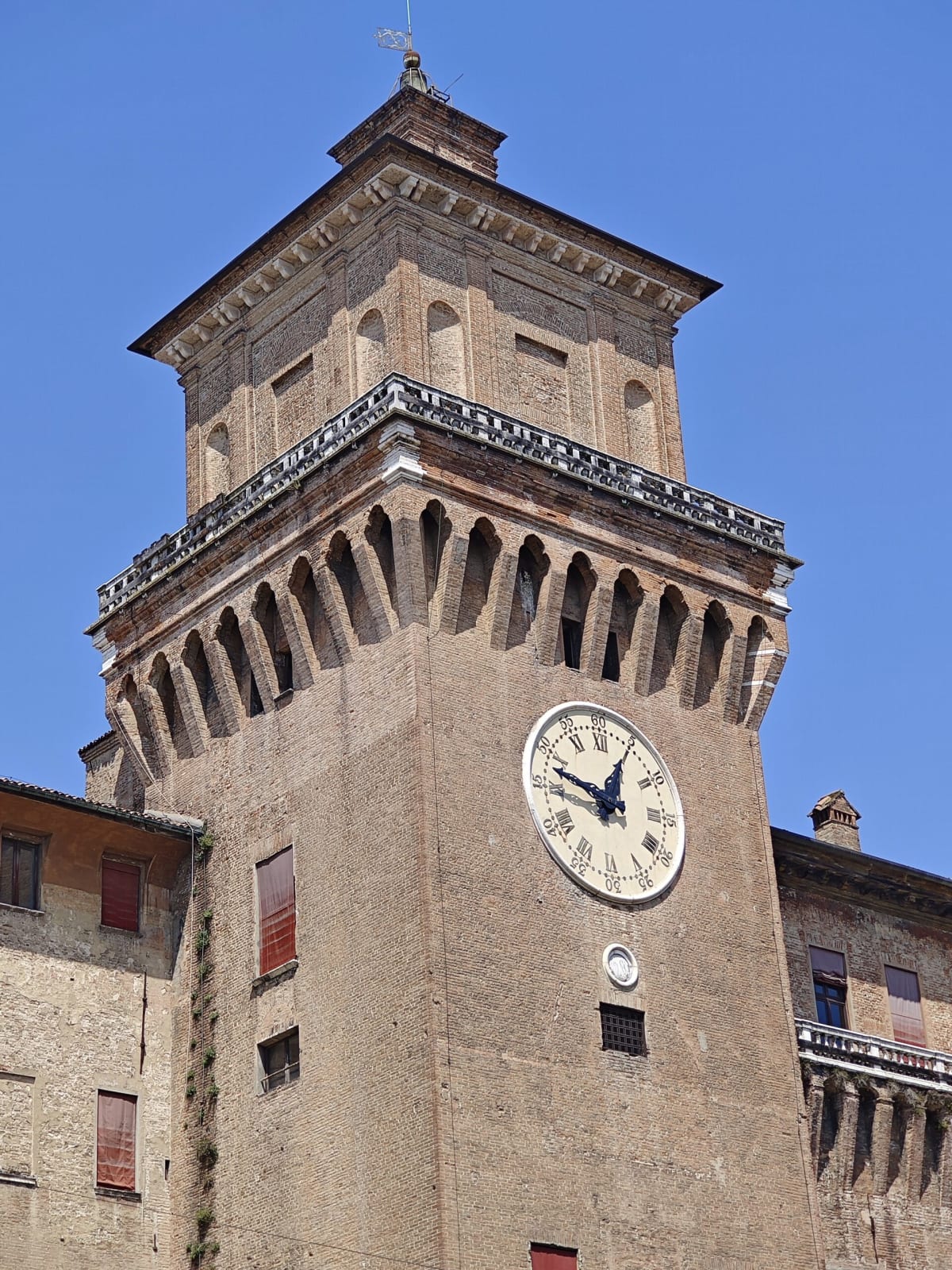 A close view of the castle's clock tower, brick battlements high above on a deep blue sky