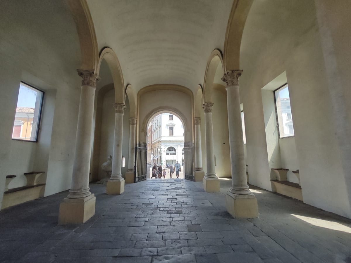 A vaulted stone passage in the old town, columns on either side and the bright street at the end