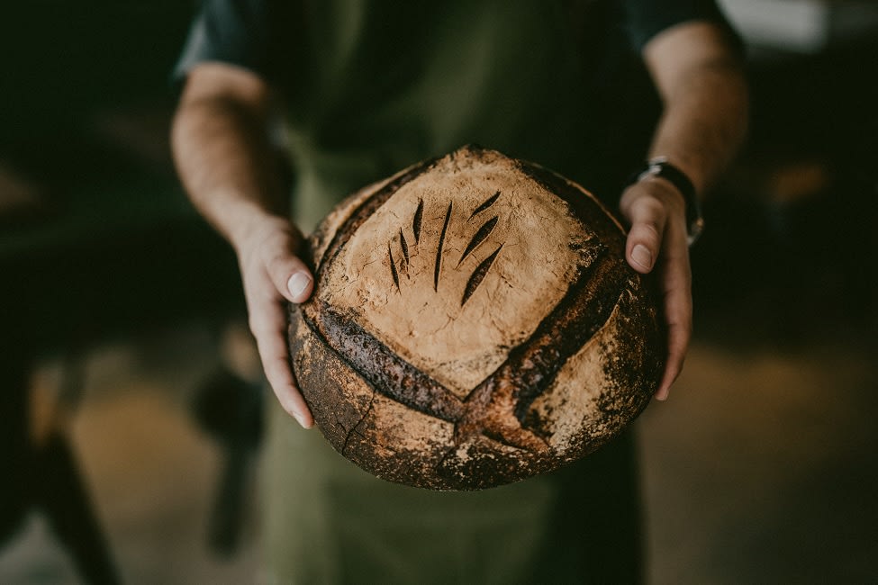 Zwei Hände halten ein selbstgebackenes Brot