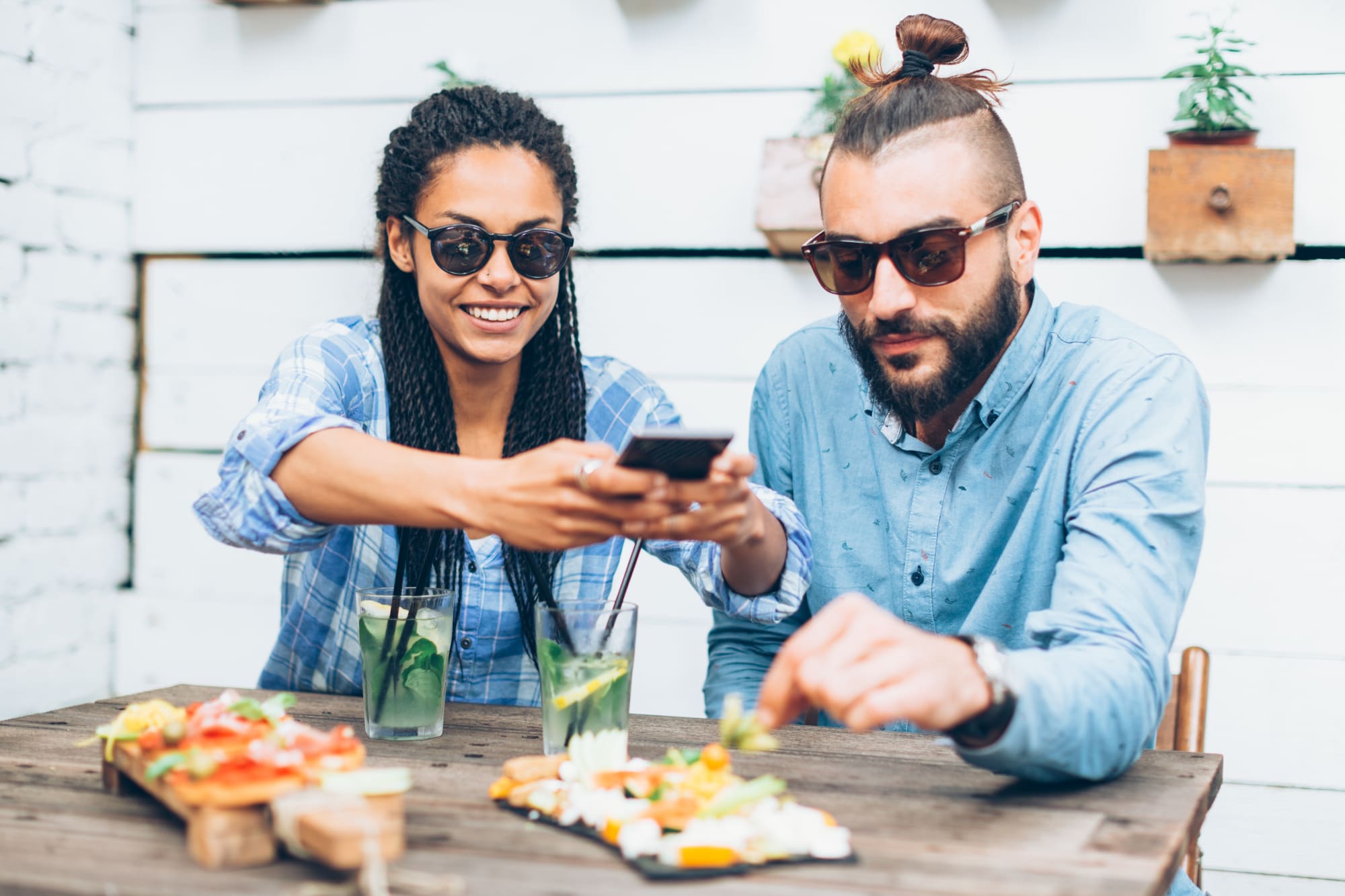 Eine Frau und ein Mann filmen Kulinarisches mit dem Smartphone