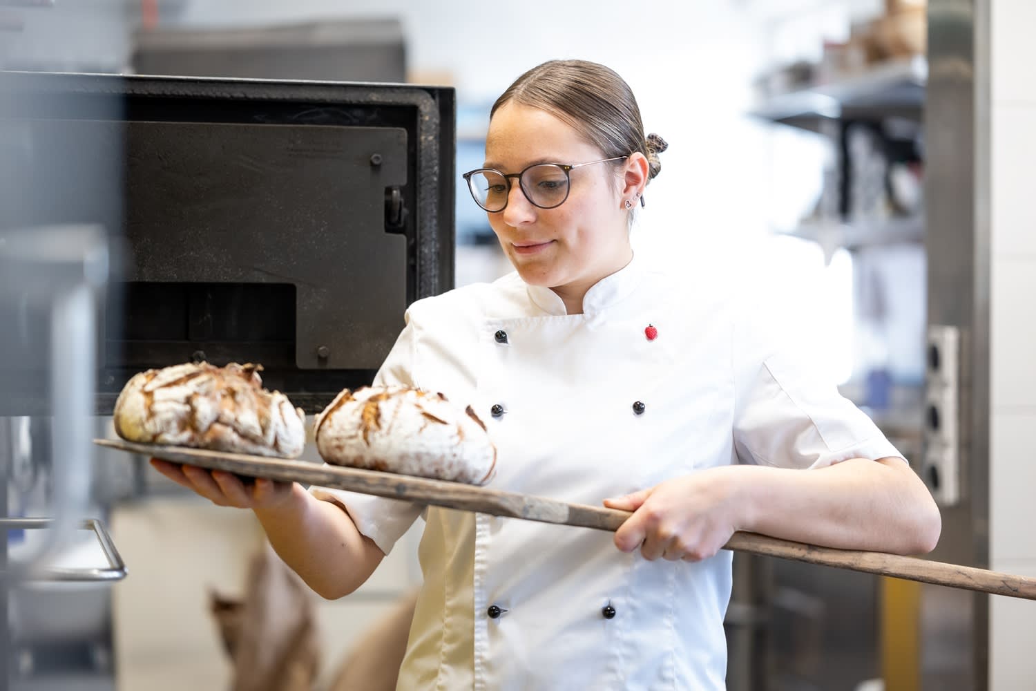 Bäckerin nimmt Holzofenbrot aus dem Holzofen