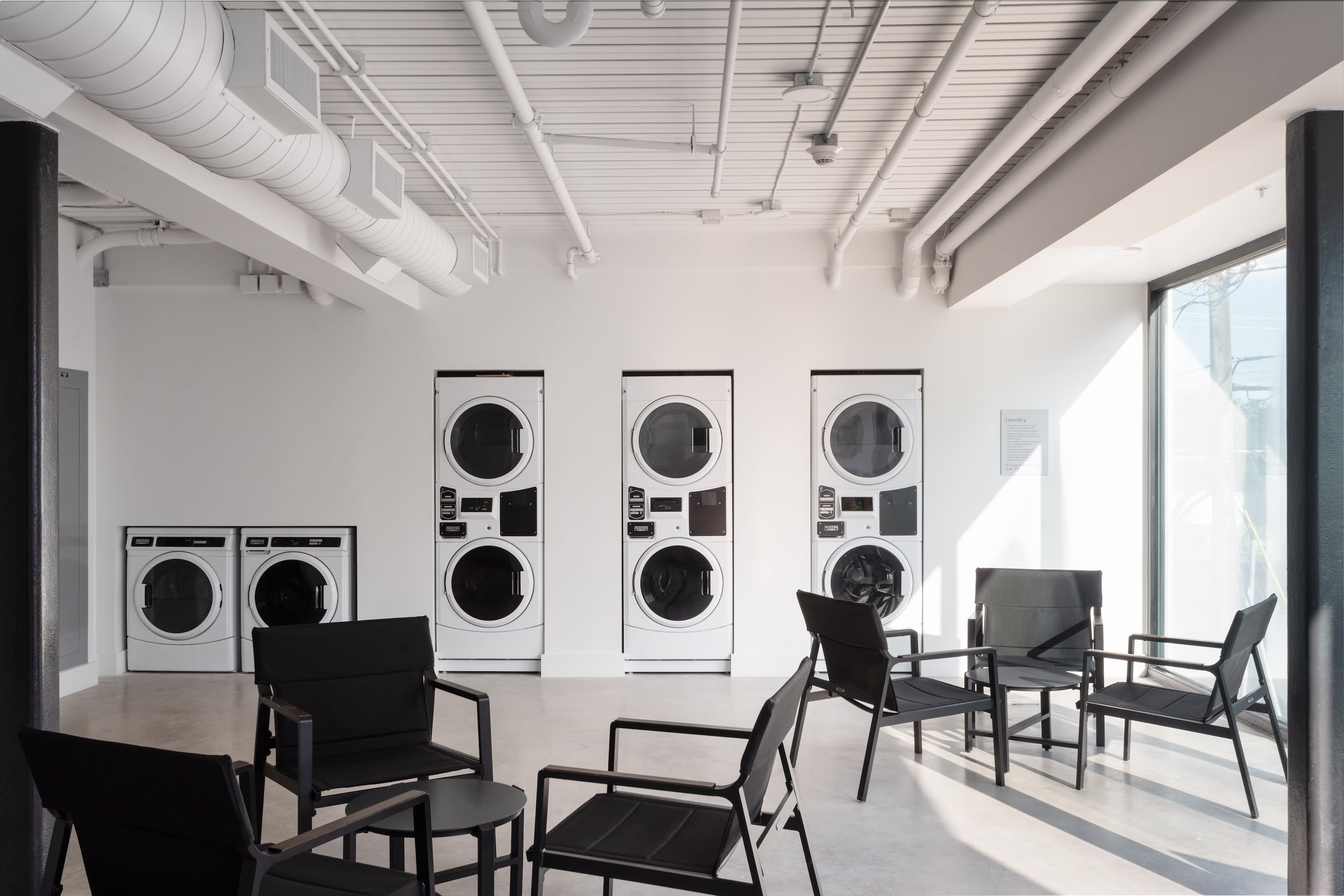 A laundry room with washers, dryers and a seating area.