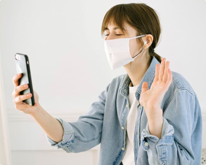 A woman in a face mask using her phone.