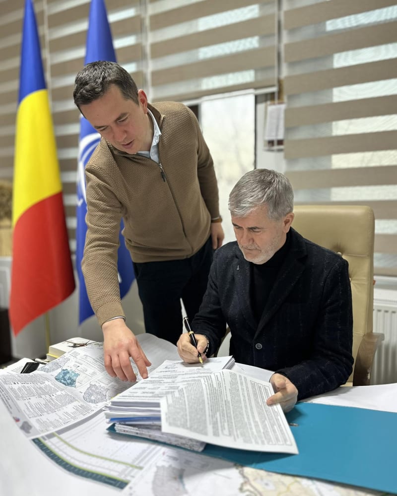Valeriu Iftime semnând documente, alături de un colaborator care indică planurile unui proiect