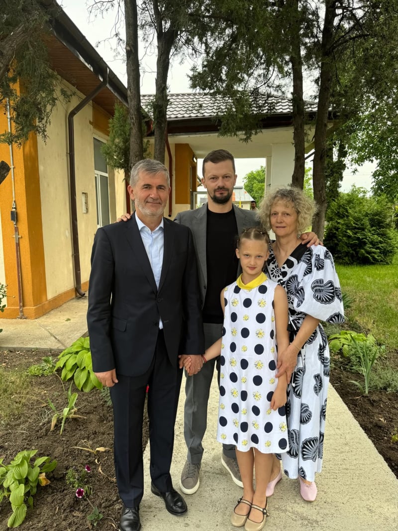 Valeriu Iftime alături de o familie, în fața unei clădiri