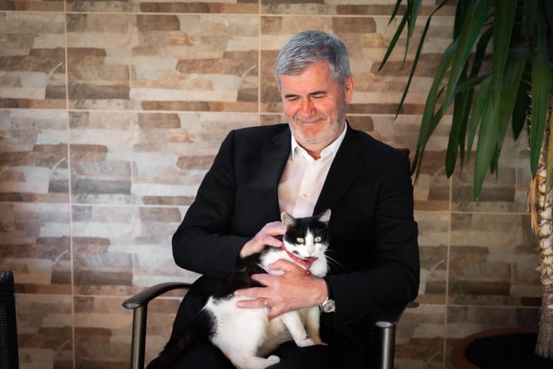 Valeriu Iftime stând pe un scaun, cu o pisică în brațe