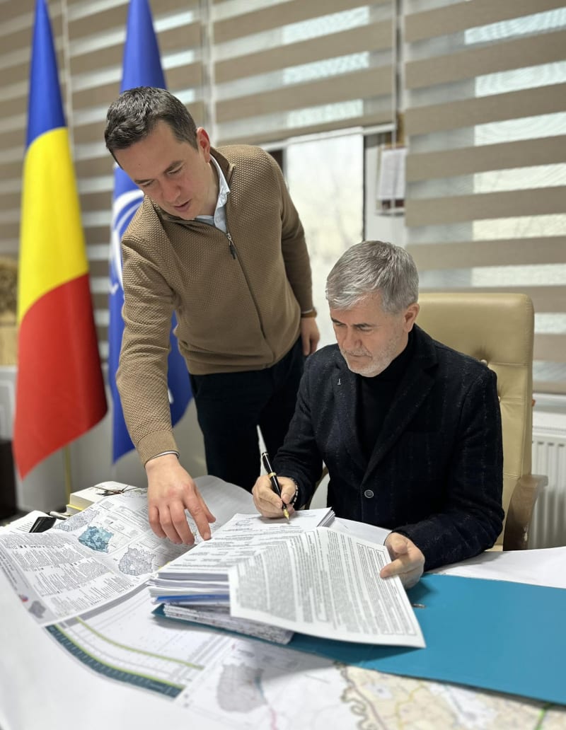 Valeriu Iftime semnând documente, alături de un colaborator care indică planurile unui proiect