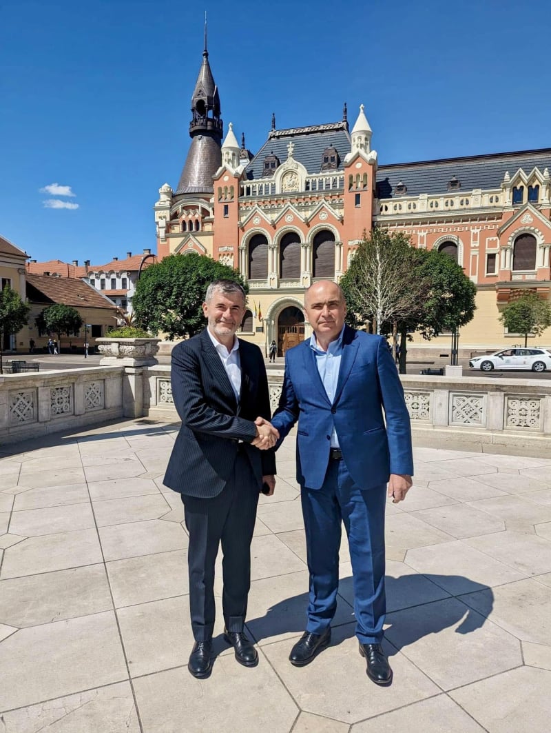 Valeriu Iftime dând mâna cu un oficial, în fața unei clădiri istorice