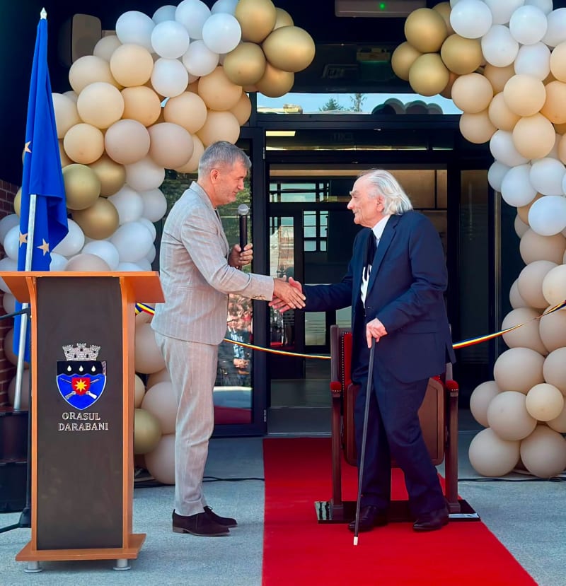 Valeriu Iftime dând mâna cu un invitat la o inaugurare, sub o arcadă de baloane
