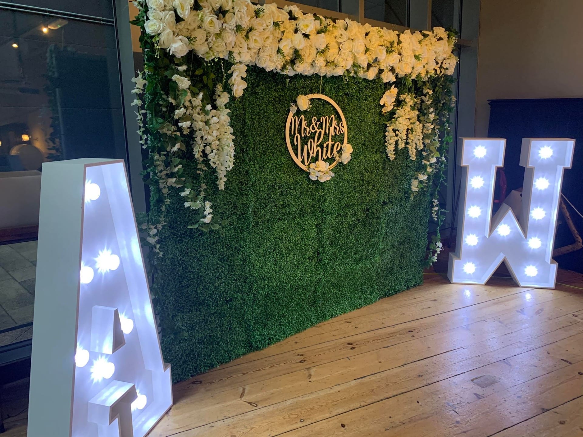  Grass backdrop with draped flowers and led letters for a wedding celebration backdrop