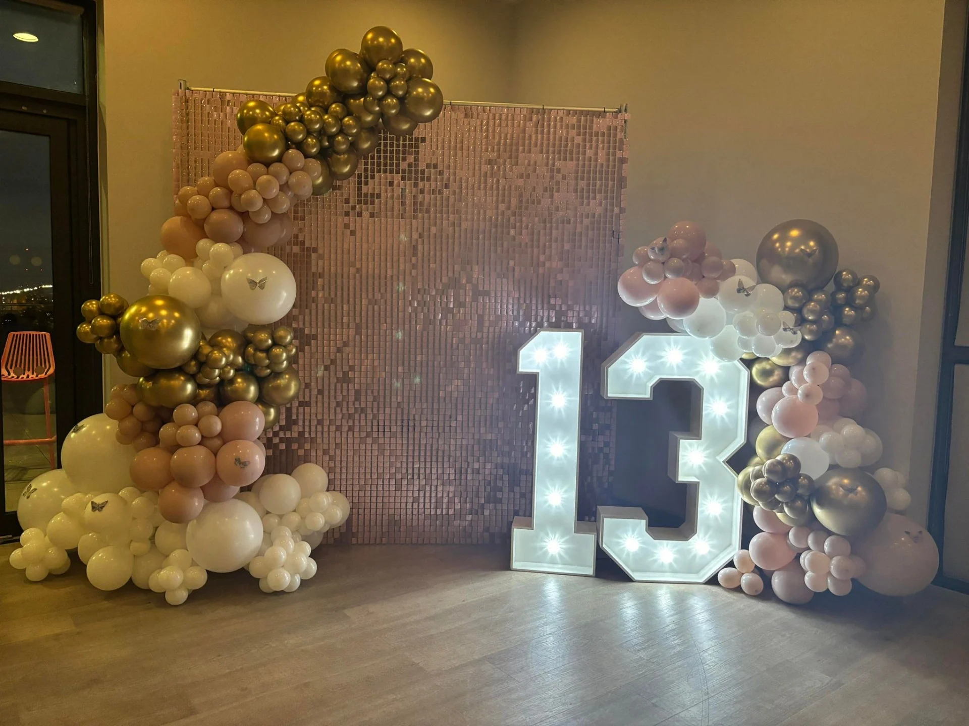 Pink shimmer wall with balloon arch and led numbers