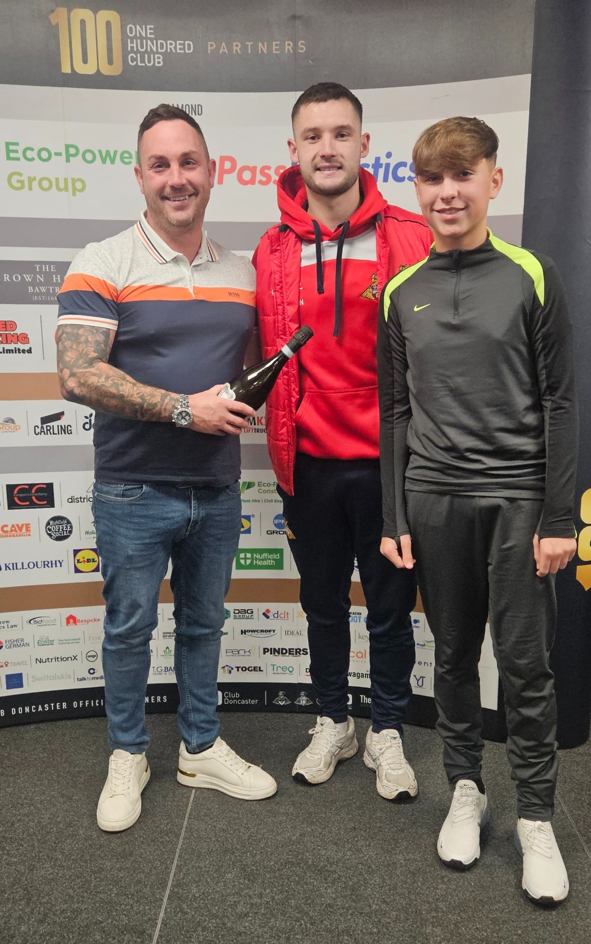 Bespoke Resin representative Gavin Howley presenting a matchday gift alongside Doncaster Rovers players and his son Chace at a sponsorship event.