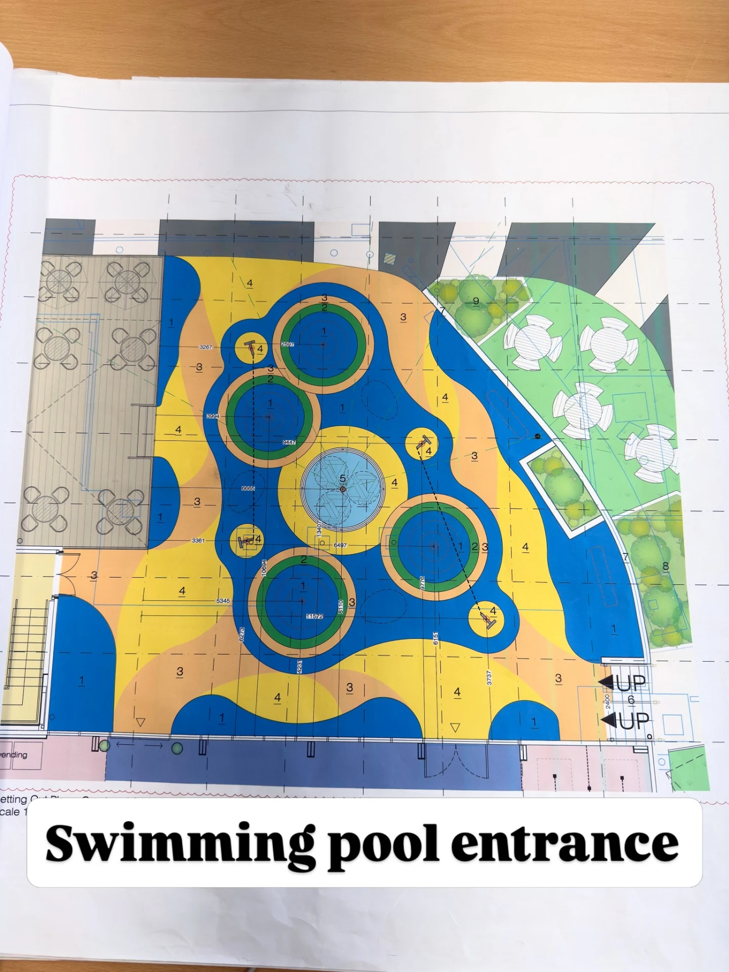 Architectural design plan of a swimming pool entrance with colorful resin bound patterns and landscaped seating areas.