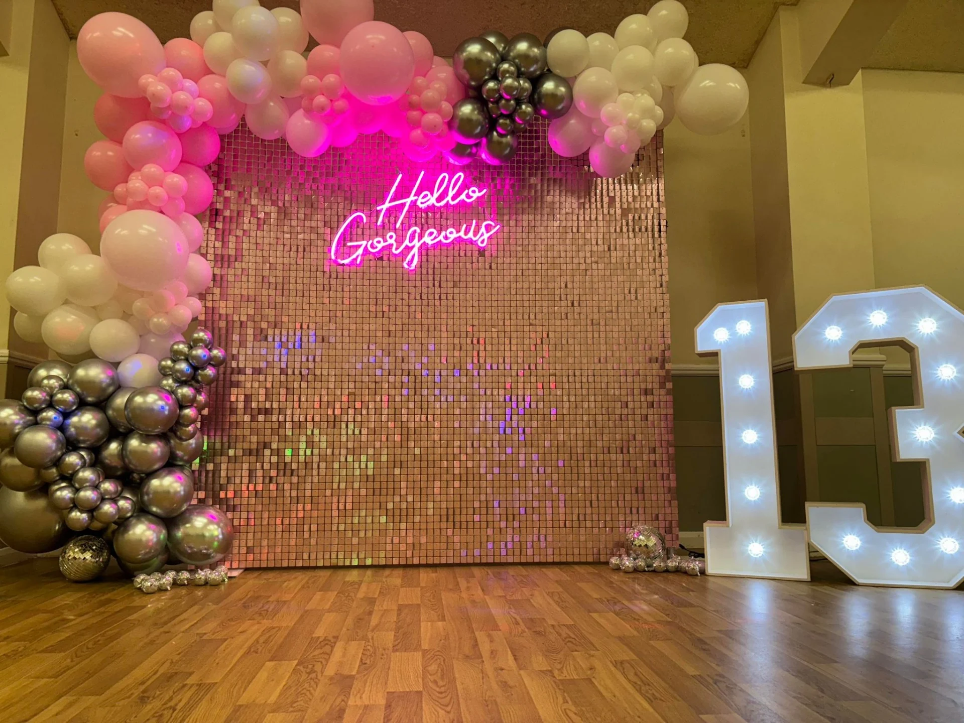 Pink sequin shimmer wall to hire with balloon arch and led numbers