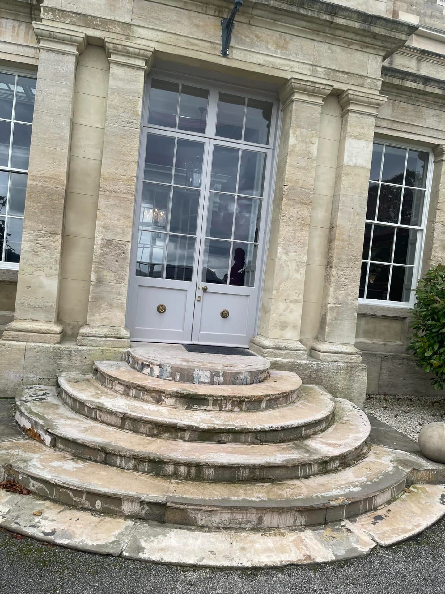 Stone entrance steps leading to a traditional building with columns and double doors.
