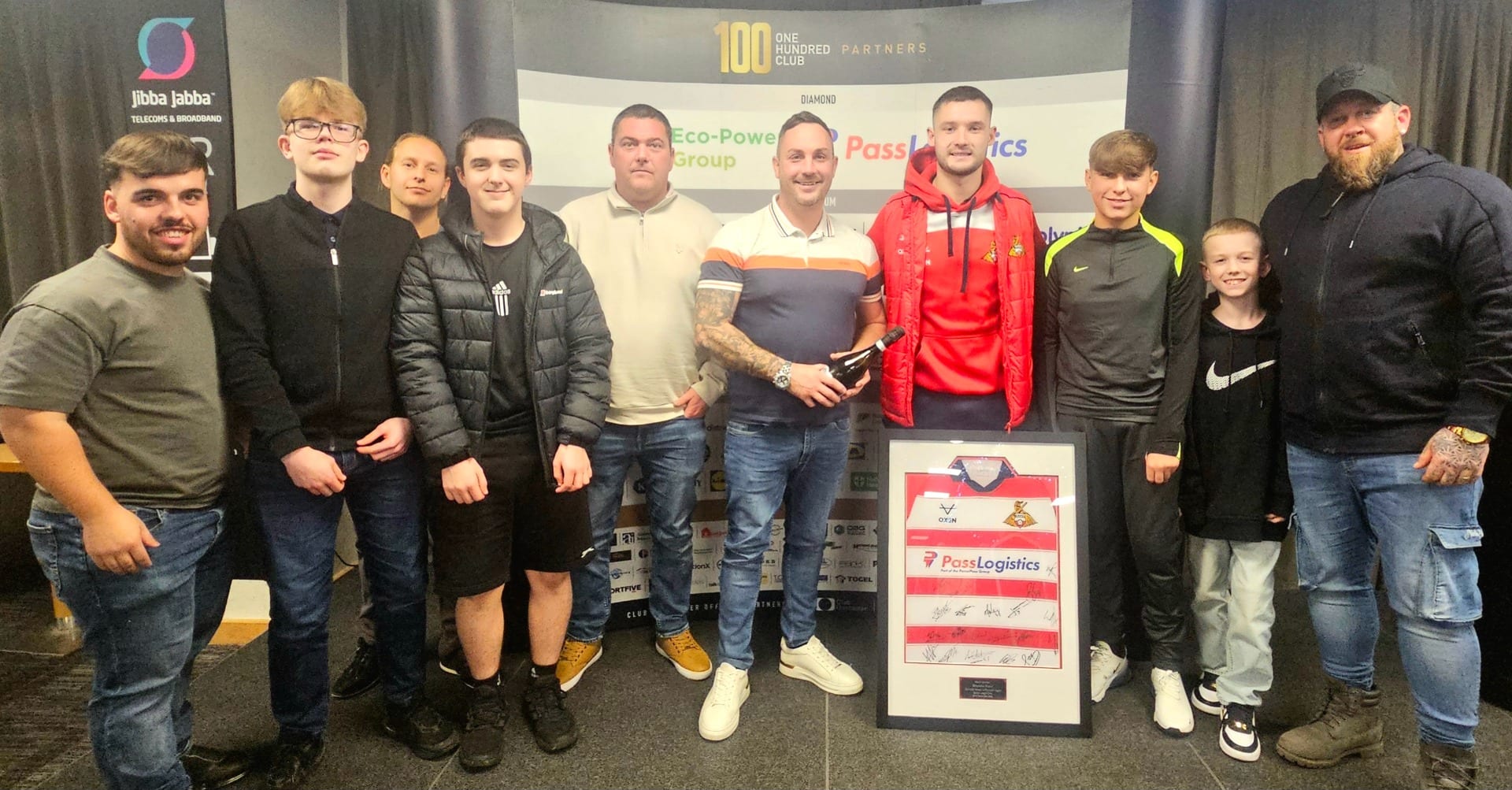 Bespoke Resin team members attending a Doncaster Rovers match sponsorship event, posing with a signed football shirt.