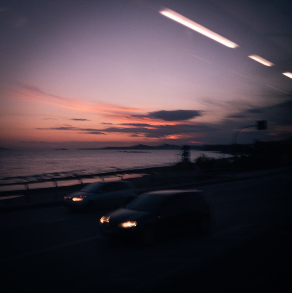 View out of the window from a coach traveling along the Aegean coast at dusk in Greece.