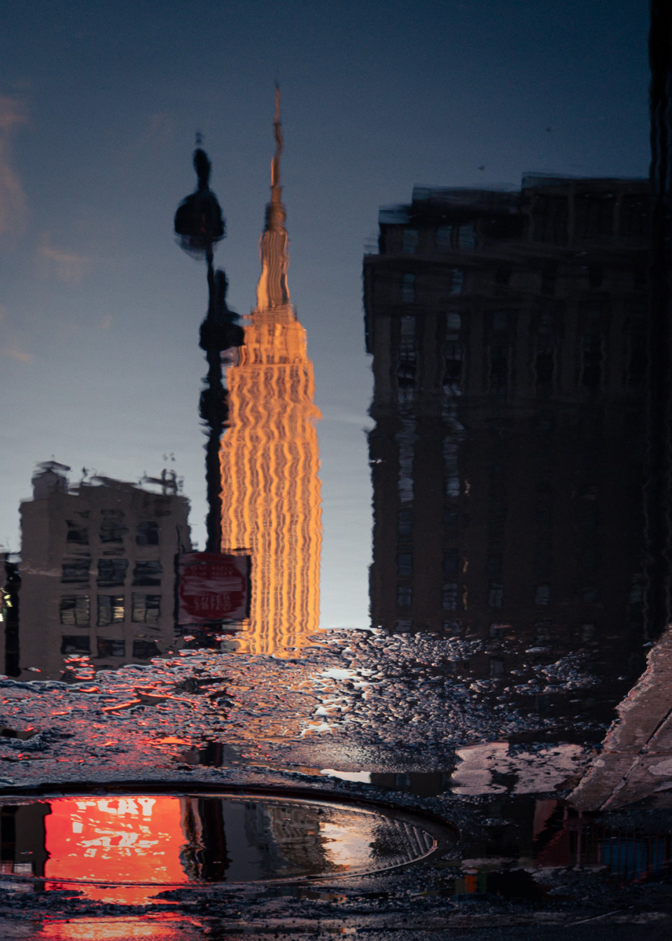Reflection of the Empire State Building in a water puddle in New York City.