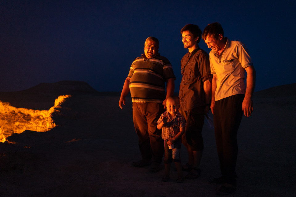 Men and baby standing next to Darvaza gas crater, also known as Door to Hell, in Turkmenistan.