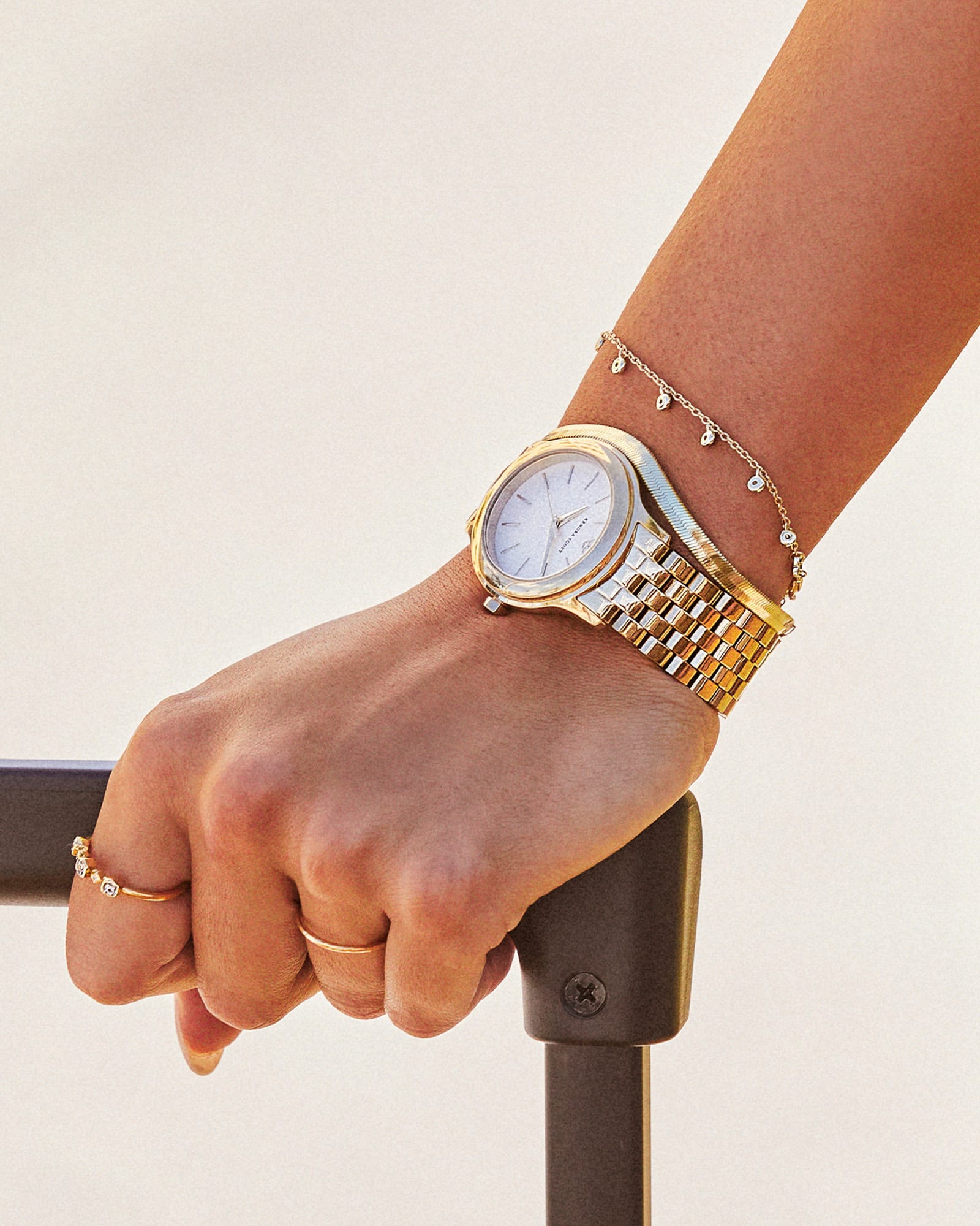 women wrist on a suitcase wearing a a gold watch and gold bracelets