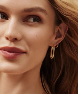 close up of women ear wearing different variation of gold huggie earrings