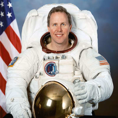 Tom Jones headshot with American flag in the background