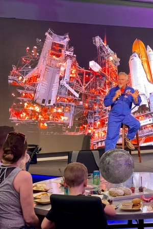 Astronaut talking to a group of visitors siting at a table during Chat With An Astronaut at Kennedy Space Center