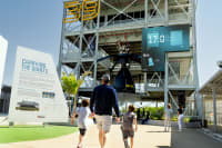 The test fire rocket engine mounted from the third floor of the gantry. When the show countdown reaches zero, it comes to life in a roar of light, sound, mist, and static vibration. Nearby, an animation test loops on outward-facing monitors.
