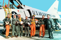 Mercury seven astronauts posing outside of an aircraft