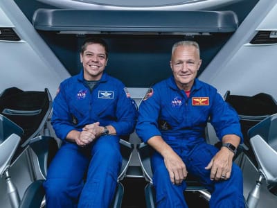 Two astronauts posing for a photo inside of a rocket