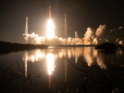 Framed by vegetation in the foreground and against the backdrop of a black night sky, NASA’s SLS (Space Launch System) rocket carrying the Orion spacecraft launches on the Artemis I flight test on Nov. 16, 2022, from Launch Complex 39B at NASA’s Kennedy Space Center in Florida.