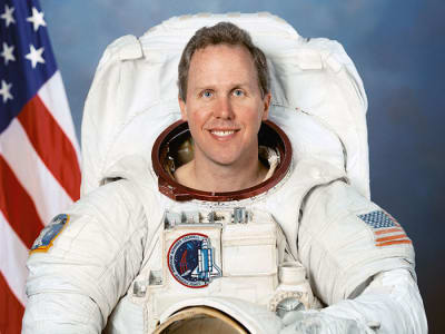 Tom Jones headshot with American flag in the background