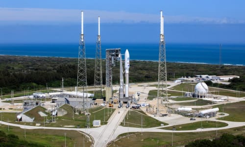 Aerial view of Space Launch Complex 41. Three lightning towers surround a United Launch Alliance Atlas V 541 Rocket. In the background is the Atlantic Ocean.