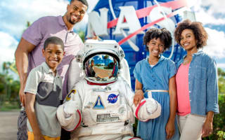Family posing with an astronaut in front of the NASA fixture