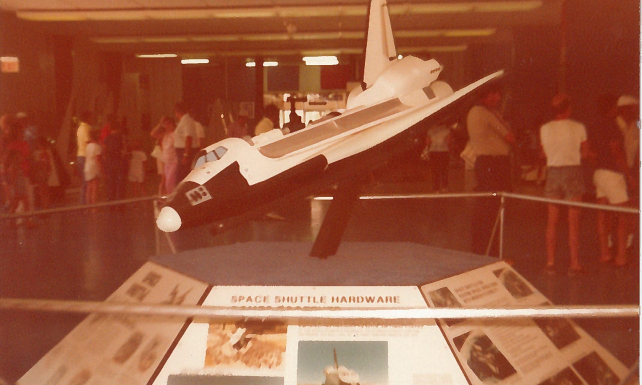 This photograph is from the official NASA Kennedy Space Center digital archive, capturing a prominent indoor display from the late 1970s and early 1980s. This display inside the Kennedy Space Center Visitor Complex was titled "Space Shuttle Hardware." It was designed to introduce the public to the technology behind the upcoming Space Shuttle program while the vehicles were still actively being engineered and tested.