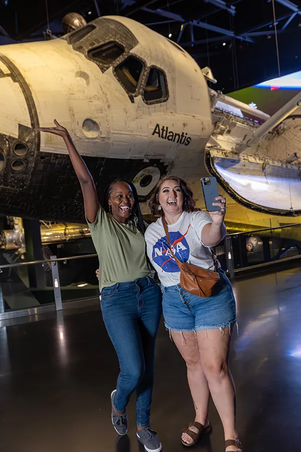 Two women taking a selfie in front of Space Shuttle Atlantis