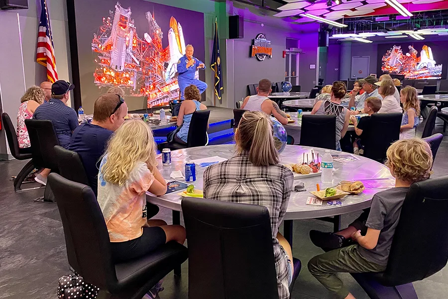 Visitors siting at tables listening to an astronaut speak