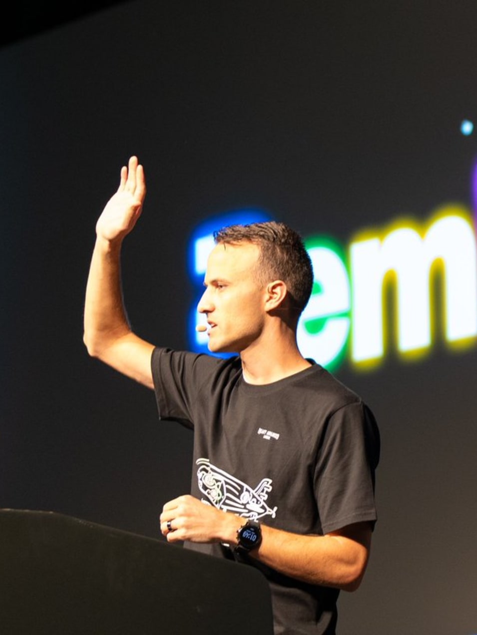 Kent on stage raising his hand with the Remix logo behind him