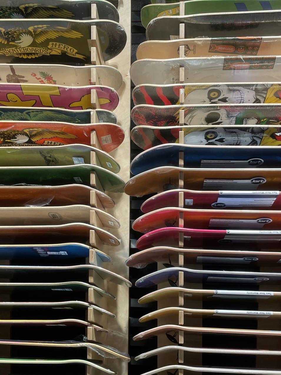A rack filled with lots of different colored skateboards