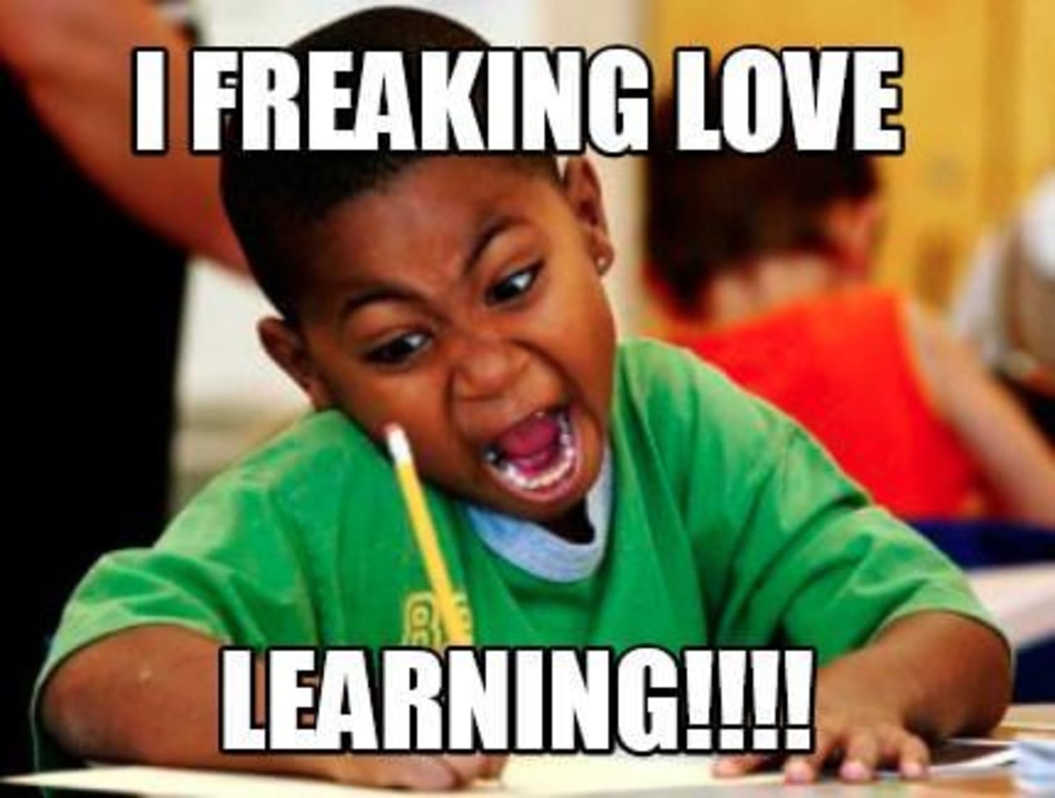 A boy with an enthusiastic face working in a classroom with the words "I freaking love learning"