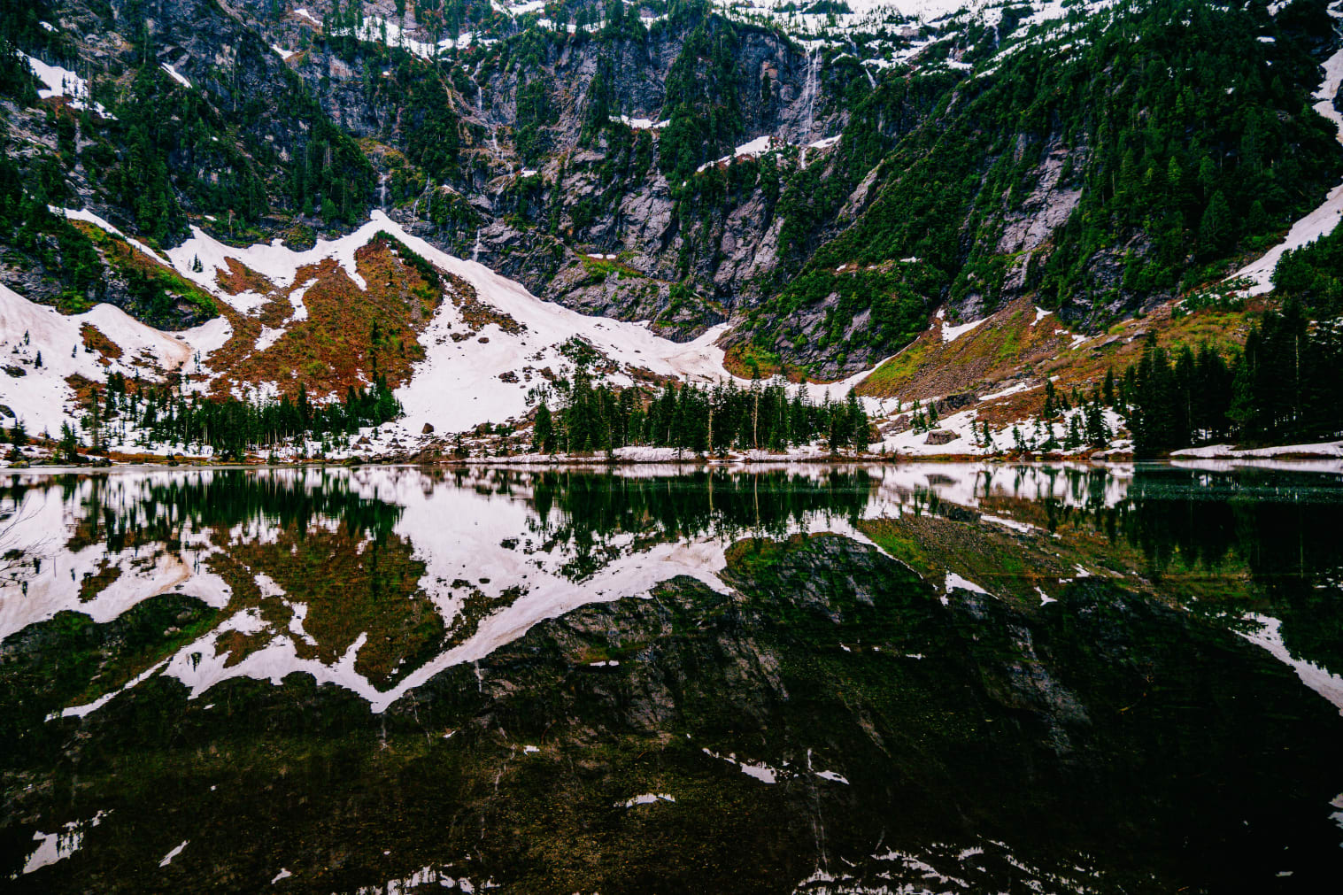 A mountain range with a lake surrounded by snow