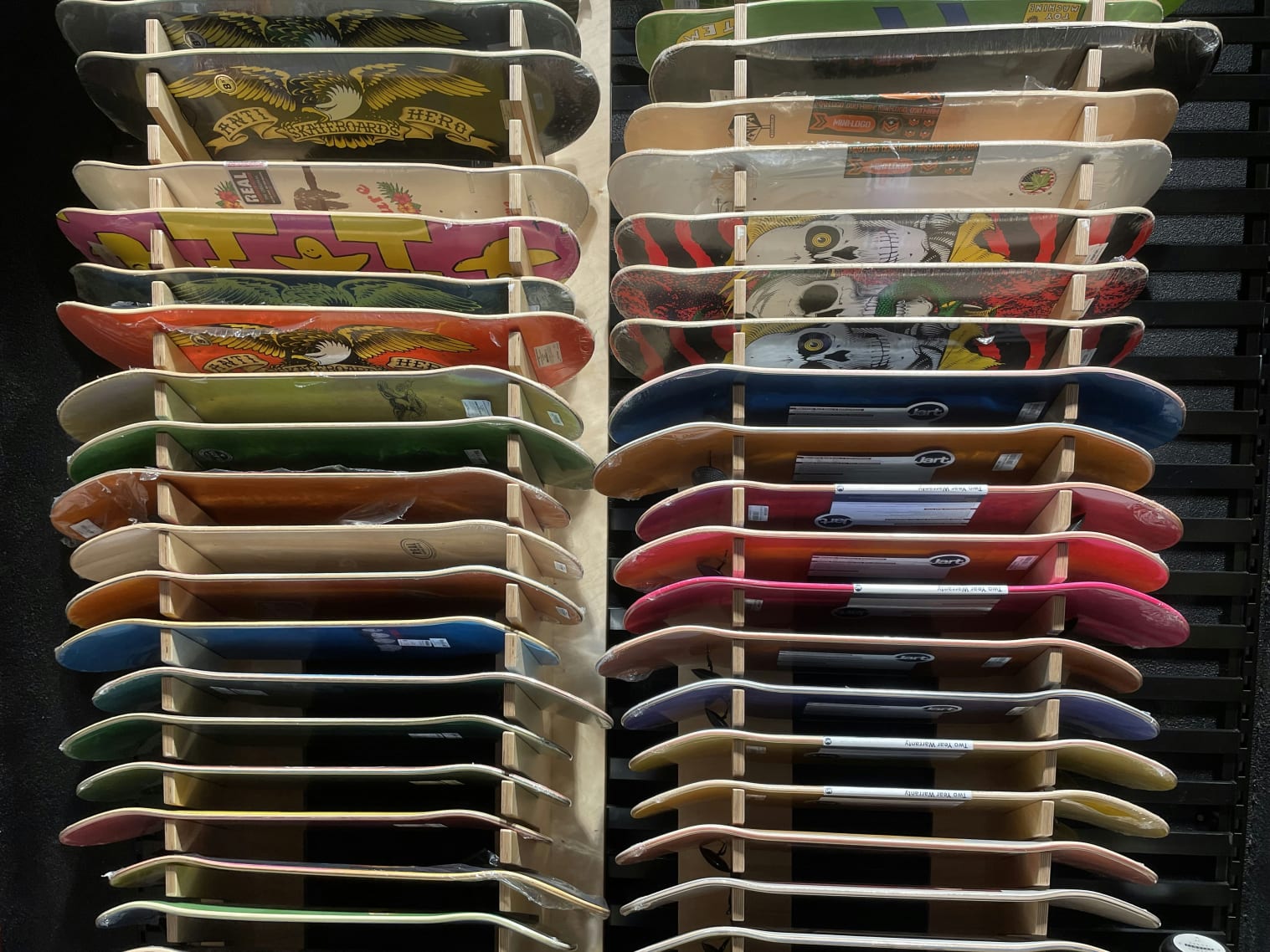 A rack filled with lots of different colored skateboards