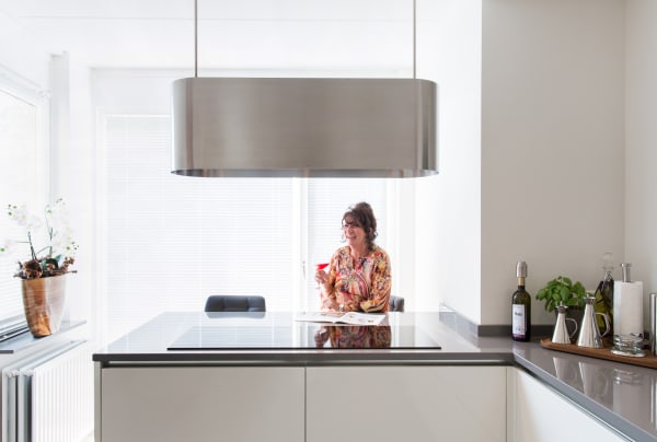 Vrouw zit aan keukeneiland met drankje