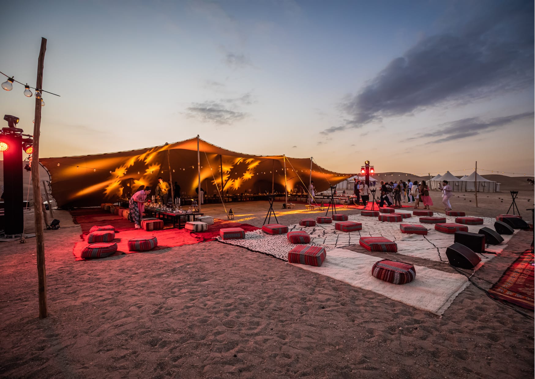 Traditional Moroccan tents in the desert at sunset and people partying
