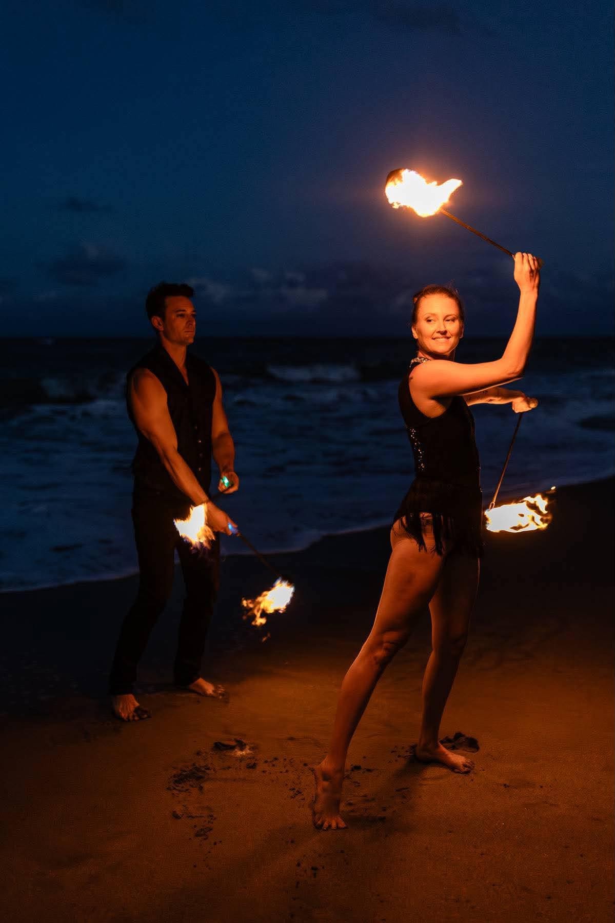 Two flow artists mid-performance with spinning fire creating glowing arcs of light
