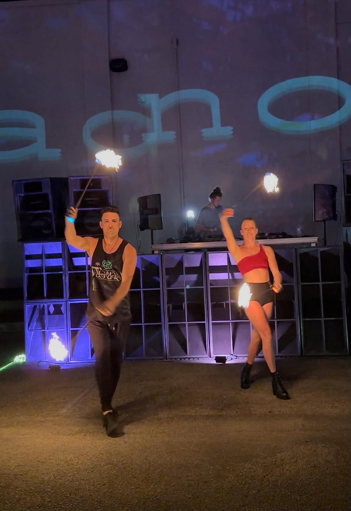 Two performers spinning fire poi at night with warm flame trails illuminated in the darkness