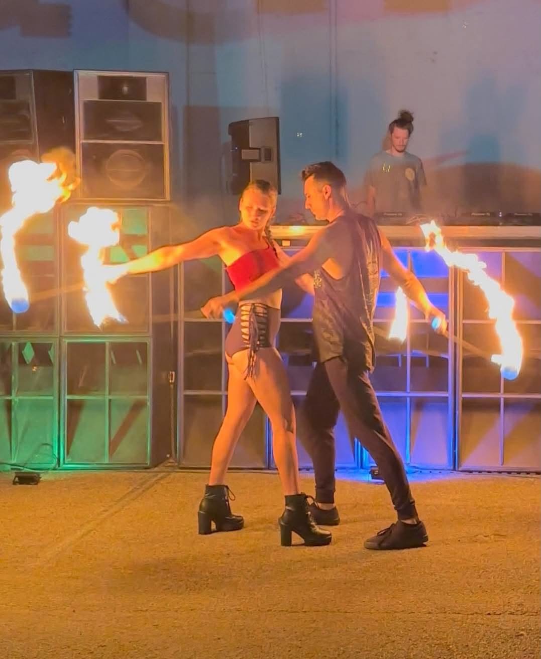 A flow artist performing with fire props under the night sky with bright trails of flame