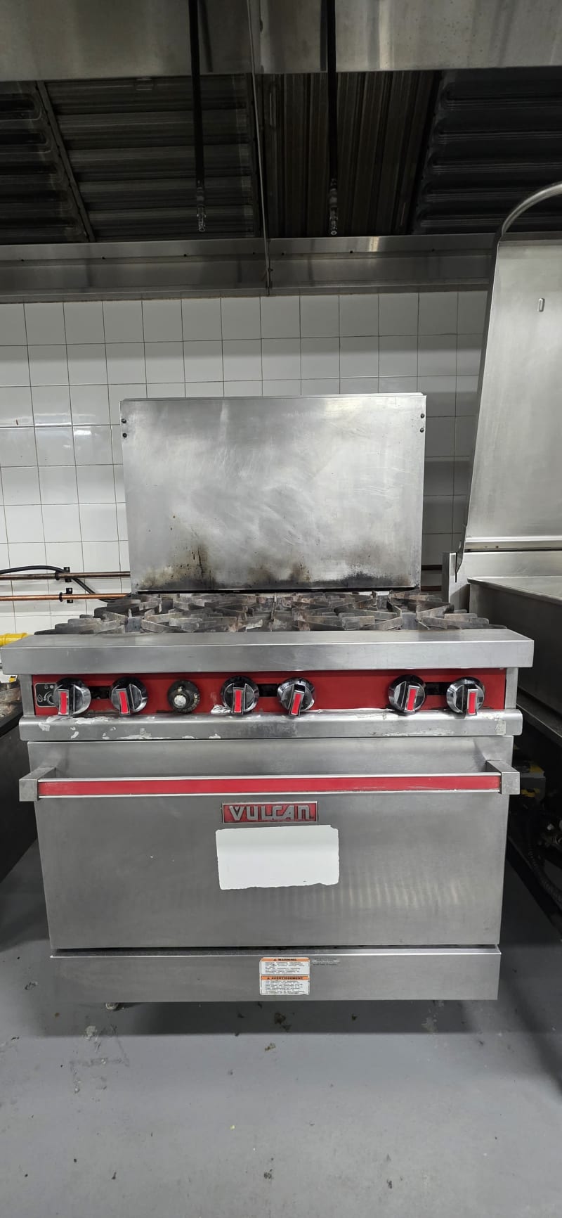Six-burner range with a stock pot in full service, steam rising